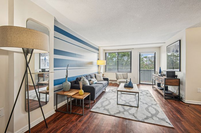Inviting living room with cozy seating, a stylish blue accent wall, and large windows for abundant natural light.