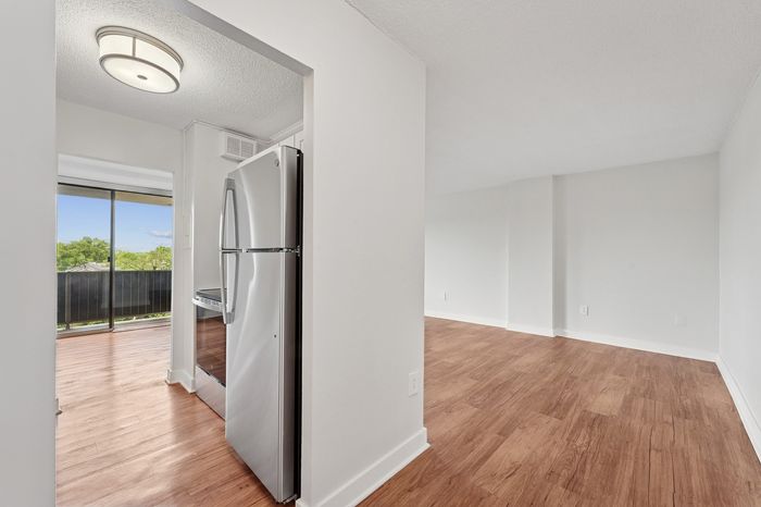 Bright and modern apartment with sleek wooden flooring, stainless steel appliances, and a scenic balcony view.