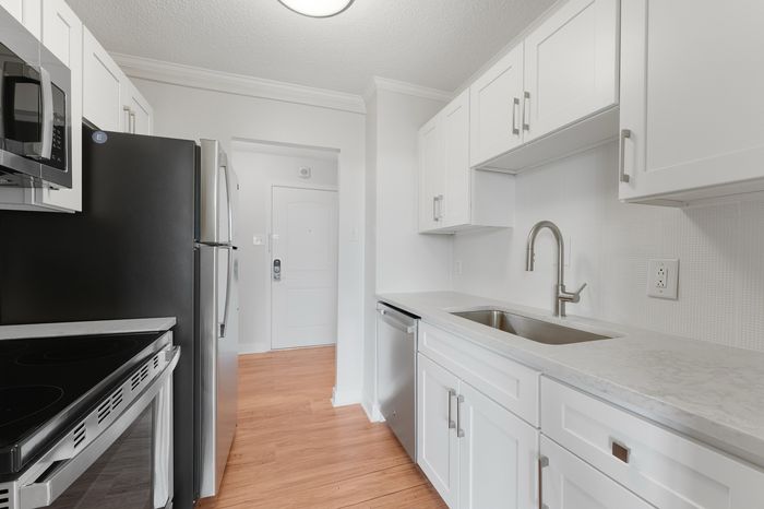 Modern kitchen with sleek stainless steel appliances, pristine white cabinetry, and polished countertops, showcasing a bright and inviting culinary space.