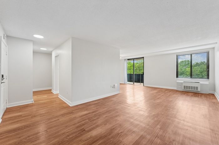 Bright and open living space with sleek hardwood floors and large windows overlooking lush greenery.