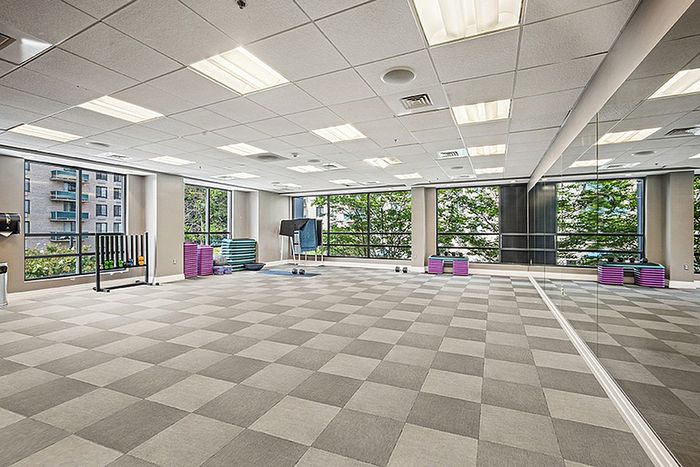 Spacious fitness studio with large windows, mirrored wall, and modern flooring, perfect for workouts in an urban setting.