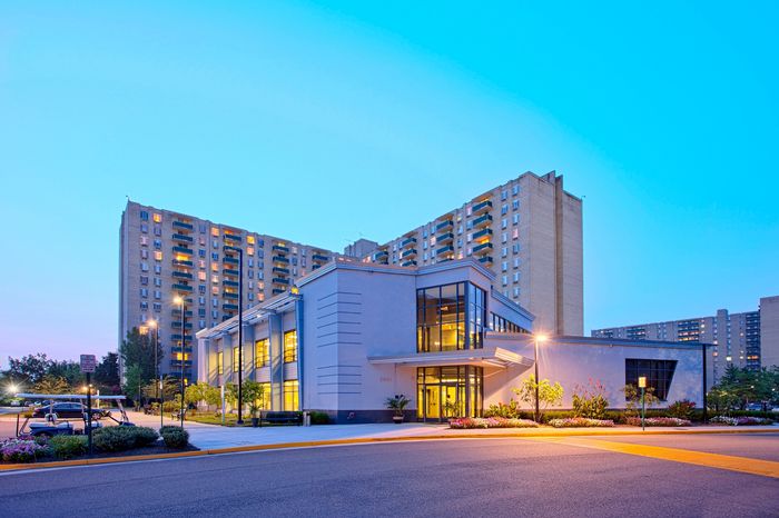 Modern apartment complex with illuminated windows and inviting landscaping under a twilight sky.