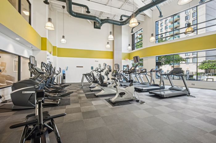 Modern fitness center with state-of-the-art exercise equipment, large bright windows, and stylish industrial design.