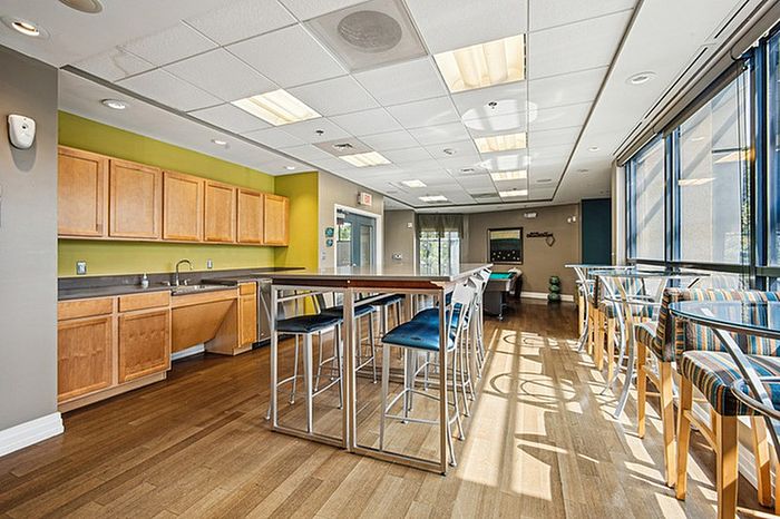 Inviting recreation room with modern kitchenette, high tables, and colorful bar stools, perfect for social gatherings.
