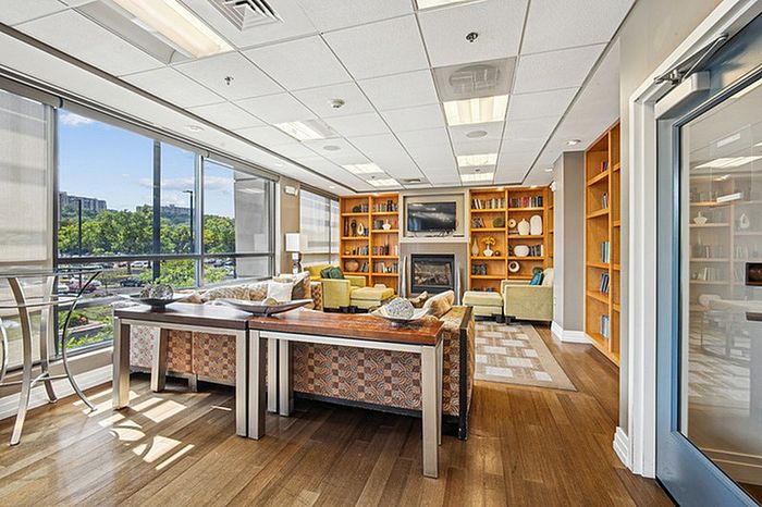Bright and inviting apartment lounge with comfortable seating, modern decor, and expansive windows offering scenic views.