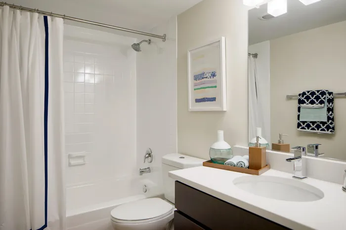 Elegant and modern bathroom with a sleek white design, featuring a fresh shower area, stylish vanity, and decorative accents.