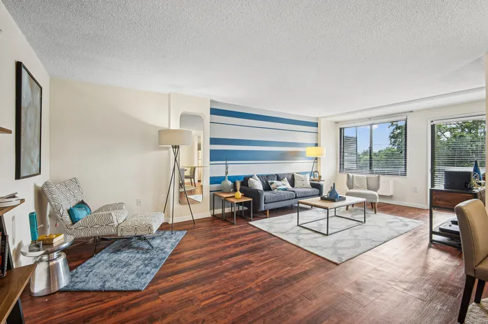 Bright and modern living room with stylish blue accent wall, cozy seating area, and large windows offering natural light.