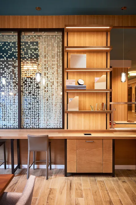 Contemporary office space with elegant wooden shelving, decorative glass partitions, and modern pendant lighting.