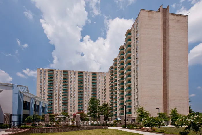 Modern high-rise apartment complex with elegant balconies against a blue sky, offering luxurious urban living.