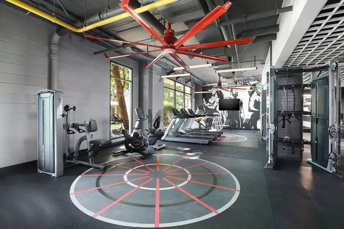 Modern gym with state-of-the-art equipment, vibrant wall art, and ample natural light, perfect for energizing workouts.