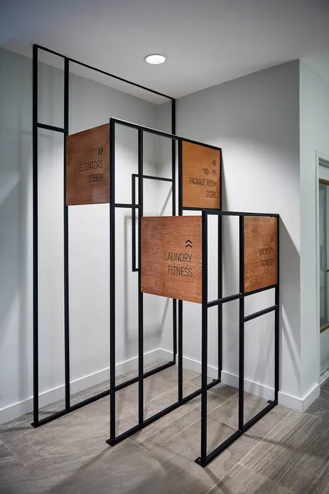 Modern sign display with clear directions to amenities like elevators, laundry, and fitness center in a stylish apartment complex.