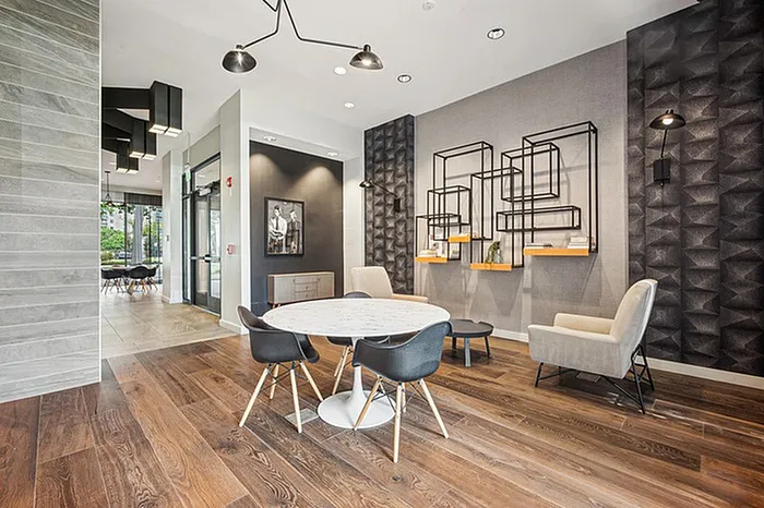 Contemporary apartment lobby with stylish seating area, modern art, and warm wood floors.