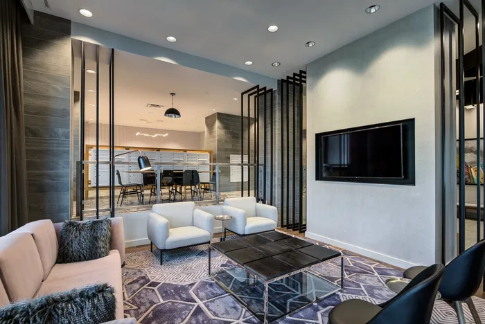Elegant modern lounge area with plush seating, a stylish coffee table, and a sleek wall-mounted TV, showcasing contemporary design and comfort.