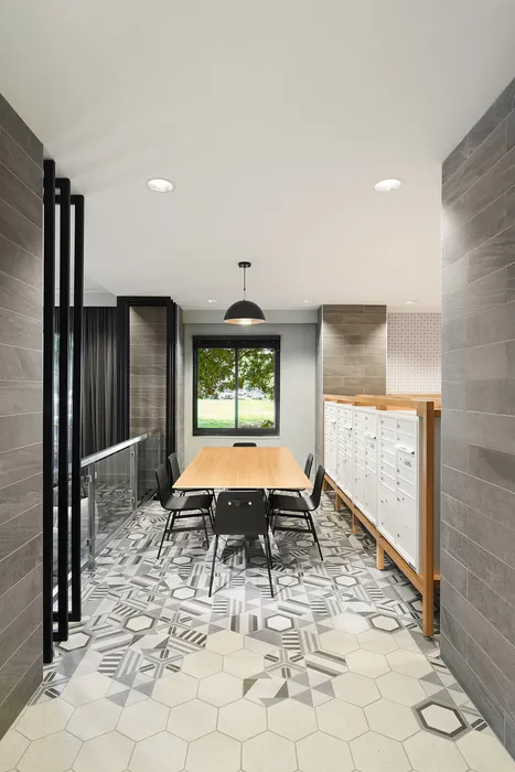 Modern office space with geometric tiled flooring, sleek table, and black chairs under stylish pendant lighting.