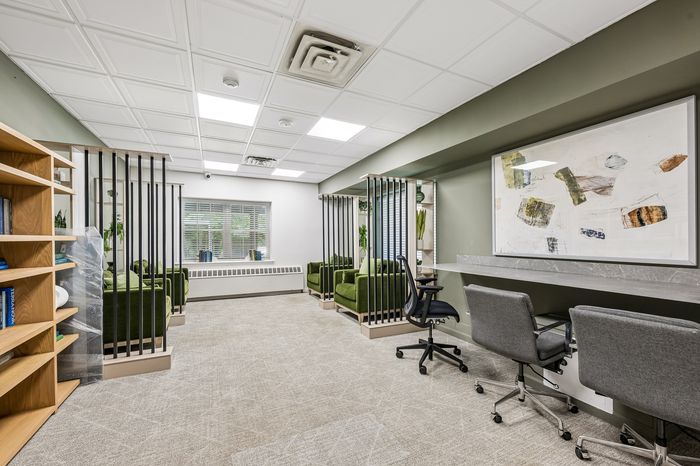 Modern office space featuring elegant green seating, stylish partitions, and a large abstract art piece, perfect for productivity and creativity.
