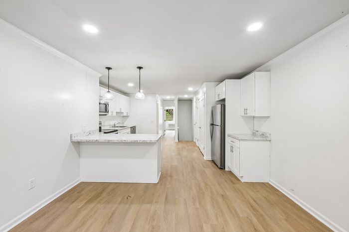 Modern open-concept kitchen with elegant marble countertops, stainless steel appliances, and bright white cabinetry, perfect for culinary enthusiasts.