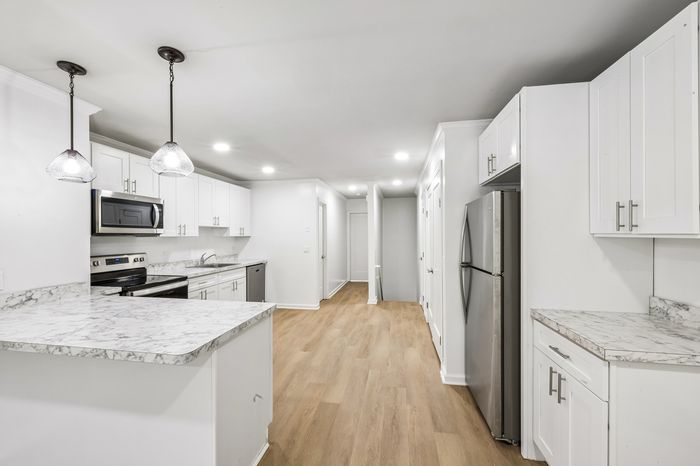 Modern kitchen design featuring sleek white cabinetry, stainless steel appliances, and elegant marble countertops.