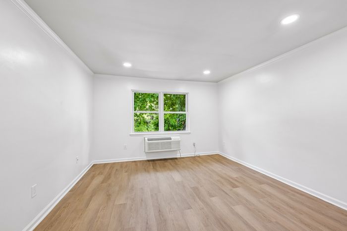 Bright and airy room with sleek wood flooring, a large window, and modern lighting creating a welcoming atmosphere.