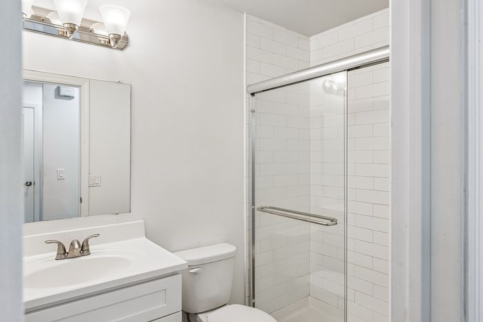 Bright and modern bathroom featuring a sleek glass-enclosed shower, elegant vanity, and contemporary lighting fixtures.