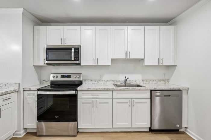 Modern kitchen with elegant white cabinetry, stainless steel appliances, and sleek marble countertops.