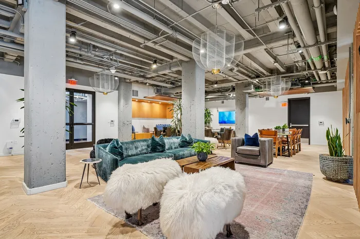 Modern industrial-style living area with plush velvet sofa, chic furry stools, and stylish pendant lighting, perfect for urban lifestyle.