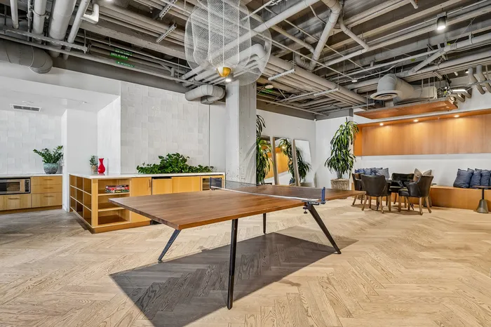 Chic industrial-style living space featuring a modern ping pong table, stylish seating area, and lush greenery.