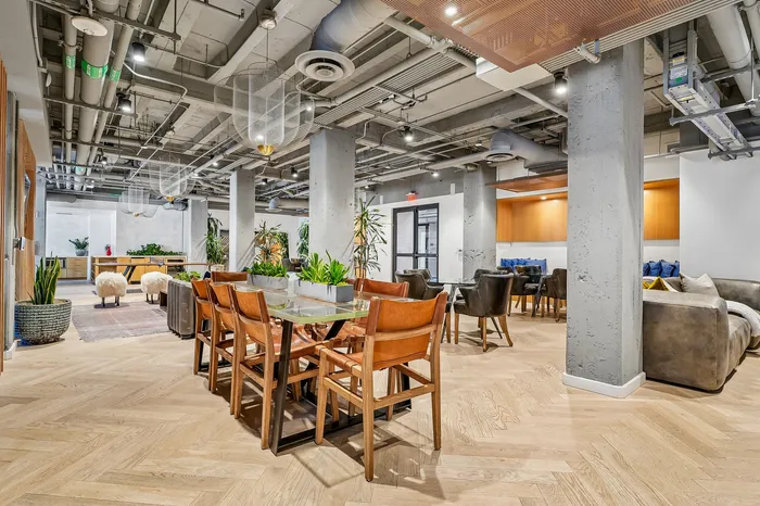 Chic and contemporary communal space featuring elegant wooden flooring, stylish seating, and lush greenery, perfect for social gatherings.