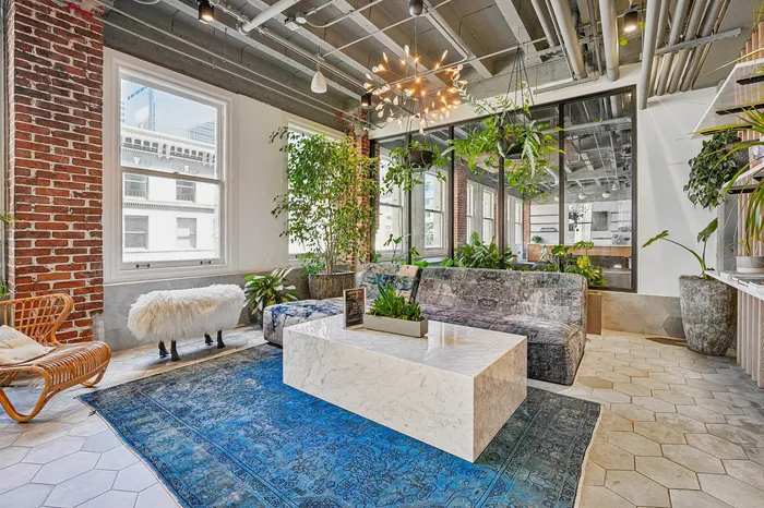 Chic urban lounge featuring exposed brick, lush greenery, and a stylish marble coffee table.