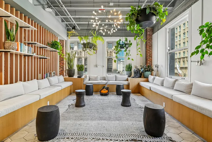 Chic, sunlit lounge with modern seating, lush greenery, and urban views, perfect for relaxation and entertainment.