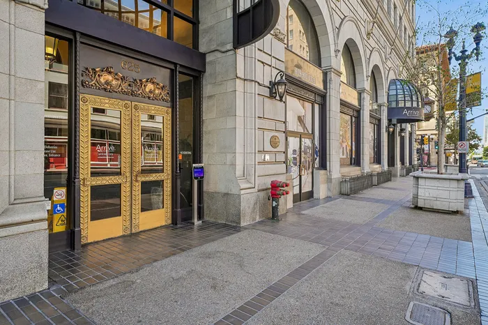 Elegant urban entrance with ornate golden doors and stone architecture, promising luxury living in a vibrant city setting.