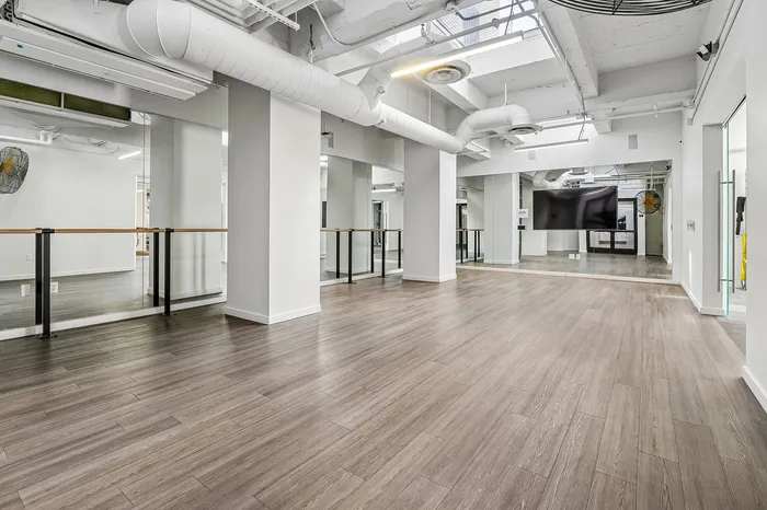 Spacious modern loft with beautiful wooden flooring, mirrors, and stylish exposed ducts for an industrial-chic look.