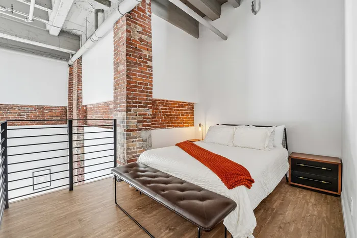 Chic loft bedroom with exposed brick walls, modern furnishings, and cozy ambiance.