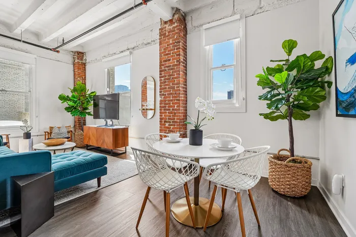 Chic urban apartment with exposed brick accents, featuring a cozy living area with stylish furniture and vibrant greenery.