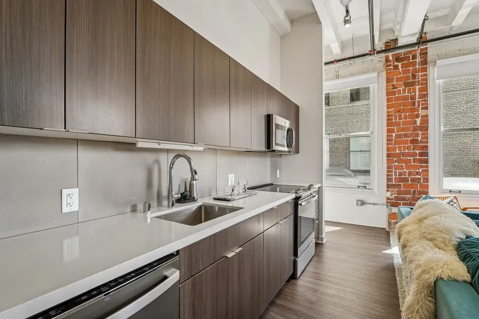 Modern kitchen with sleek cabinetry, stainless steel appliances, and an exposed brick accent wall offering a chic urban aesthetic.