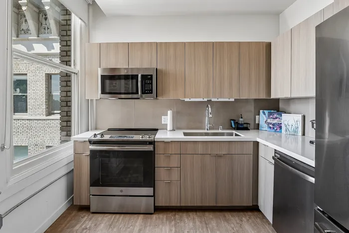 Modern kitchen with sleek appliances, elegant wooden cabinetry, and large window offering a bright view.