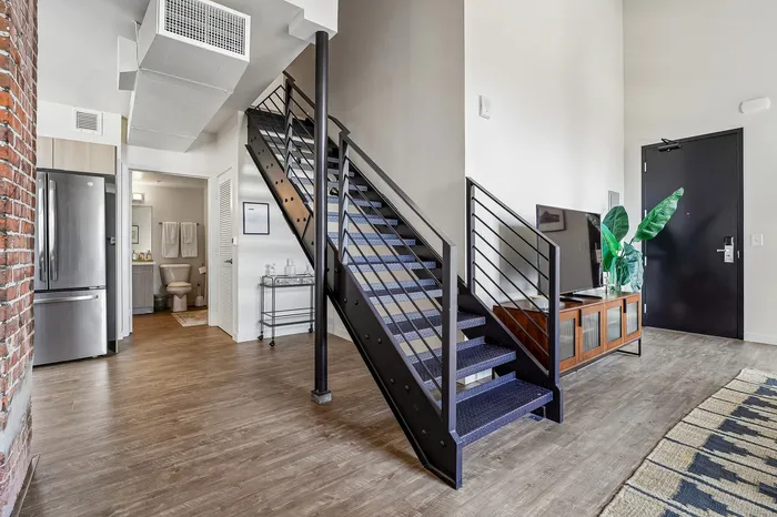 Stylish loft apartment featuring modern steel staircase, elegant wooden floors, and sleek open-plan design.