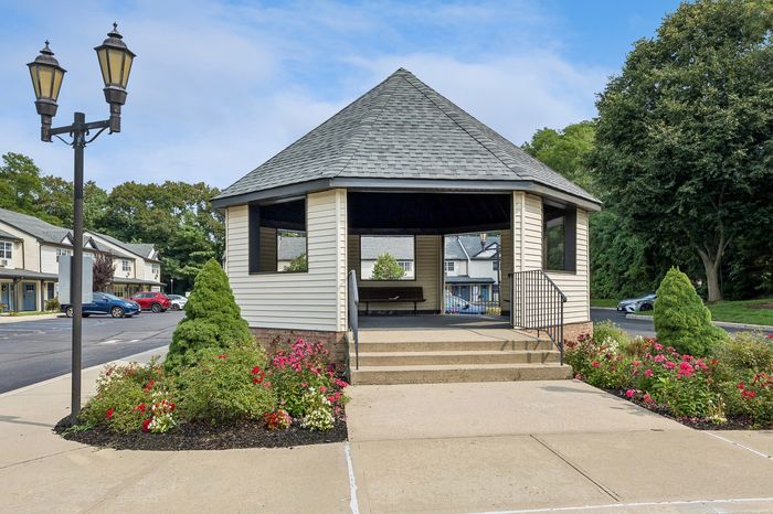 Charming gazebo surrounded by vibrant flowerbeds in a picturesque community setting.