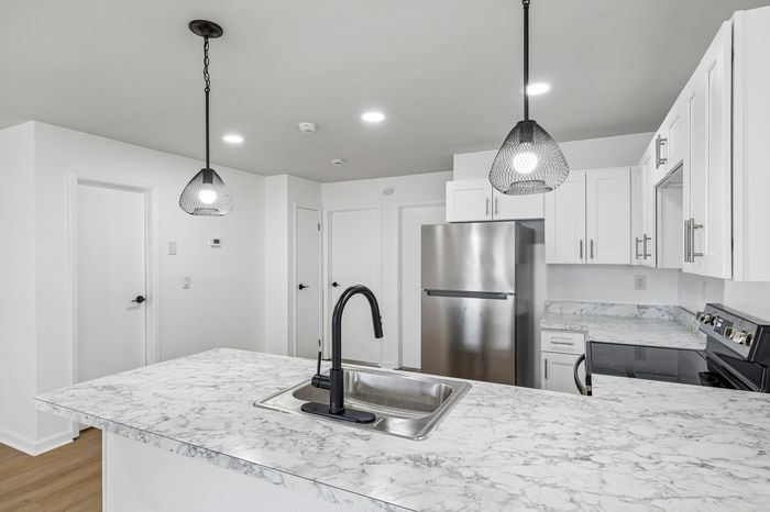 Sleek modern kitchen with elegant marble countertops, stainless steel appliances, and stylish pendant lighting.
