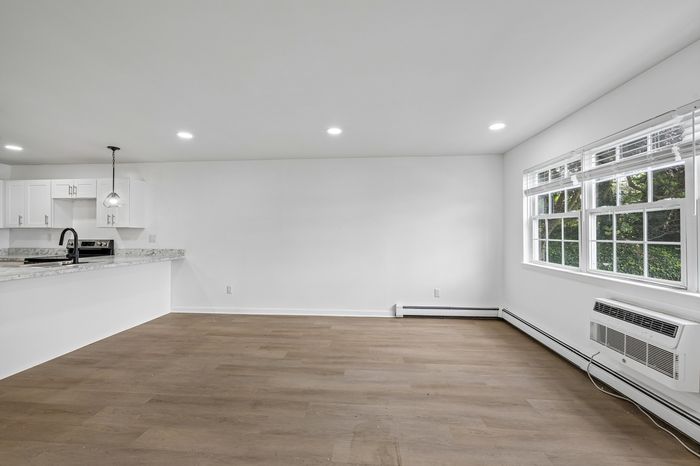 Bright open-plan living area with contemporary kitchen, marble countertops, and large windows inviting natural light.