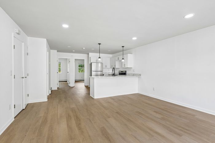Bright, open-concept apartment with sleek hardwood floors, a modern kitchen featuring elegant pendant lighting, and ample natural light.