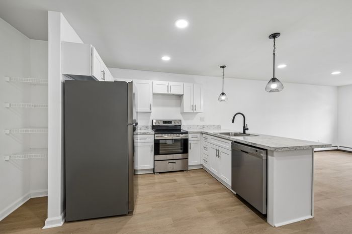 Modern kitchen with sleek stainless steel appliances, white cabinetry, and elegant marble countertops under stylish pendant lighting.