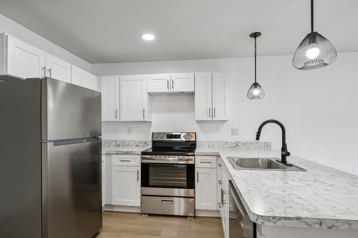 Modern kitchen with sleek stainless steel appliances, elegant marble countertops, and stylish pendant lighting.