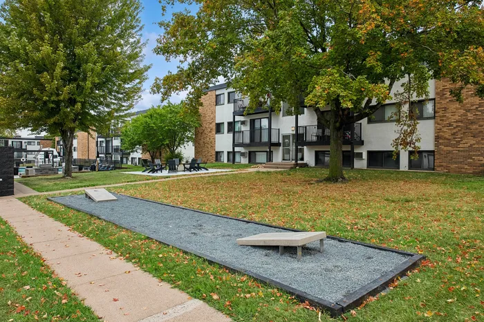 Charming residential community with lush green lawns, mature trees, and modern apartment buildings featuring spacious balconies.