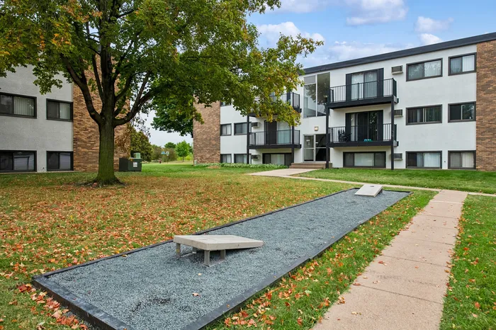 Charming apartment complex surrounded by lush greenery with a peaceful walkway, perfect for a serene living experience.