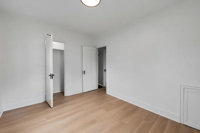 Bright, spacious bedroom with elegant wood flooring and ample closet space, inviting comfort and style.