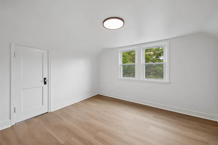 Bright, minimalist room with fresh white walls, elegant wooden flooring, and charming window view, perfect for personalization.