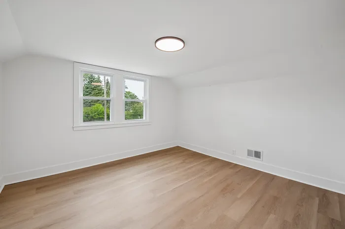 Bright, spacious room with large window, elegant hardwood floors, and stylish recessed lighting, perfect for creative customization.
