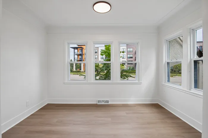 Bright and airy room with large windows offering a scenic view of modern buildings, perfect for a cozy living space or home office.