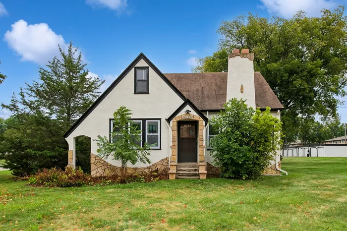 Charming Tudor-style house with a picturesque gabled roof, surrounded by lush greenery and a beautifully manicured lawn.