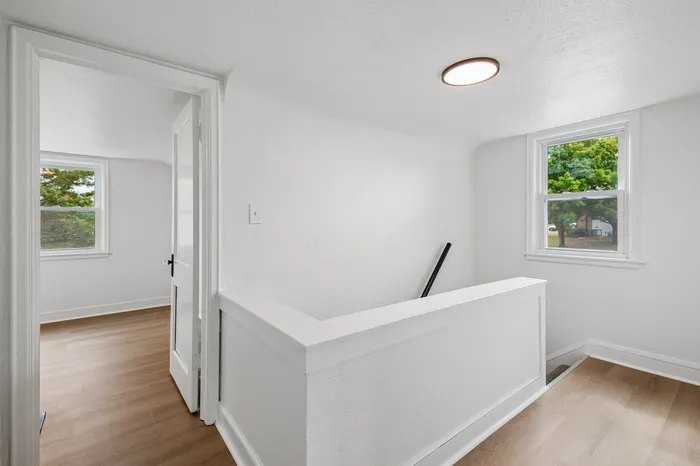 Bright, modern hallway with elegant wood floors and windows framing a lush outdoor view.